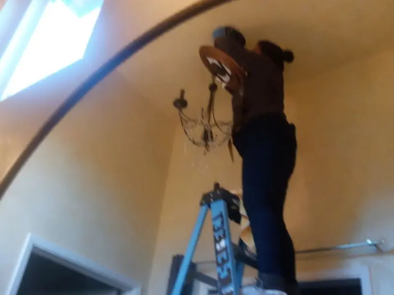 Electrician installing a chandelier in a Chartiers residence
